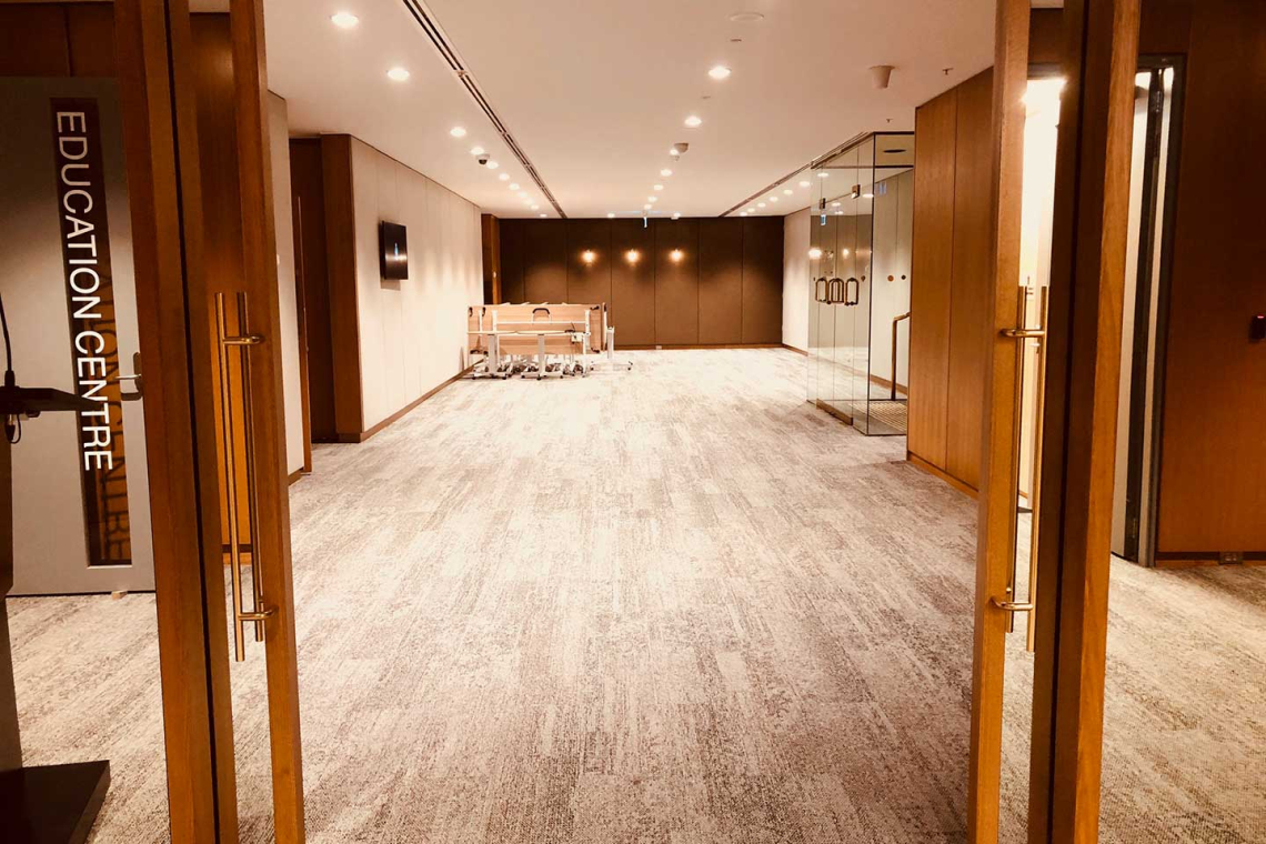 Neutral, well-lit education center hallway with wooden frames, glass doors, and a sign reading 'EDUCATION CENTRE' on the left.